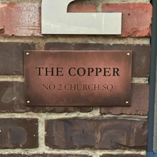 Aged copper plaque on a brick wall, made from real copper with antique patina.